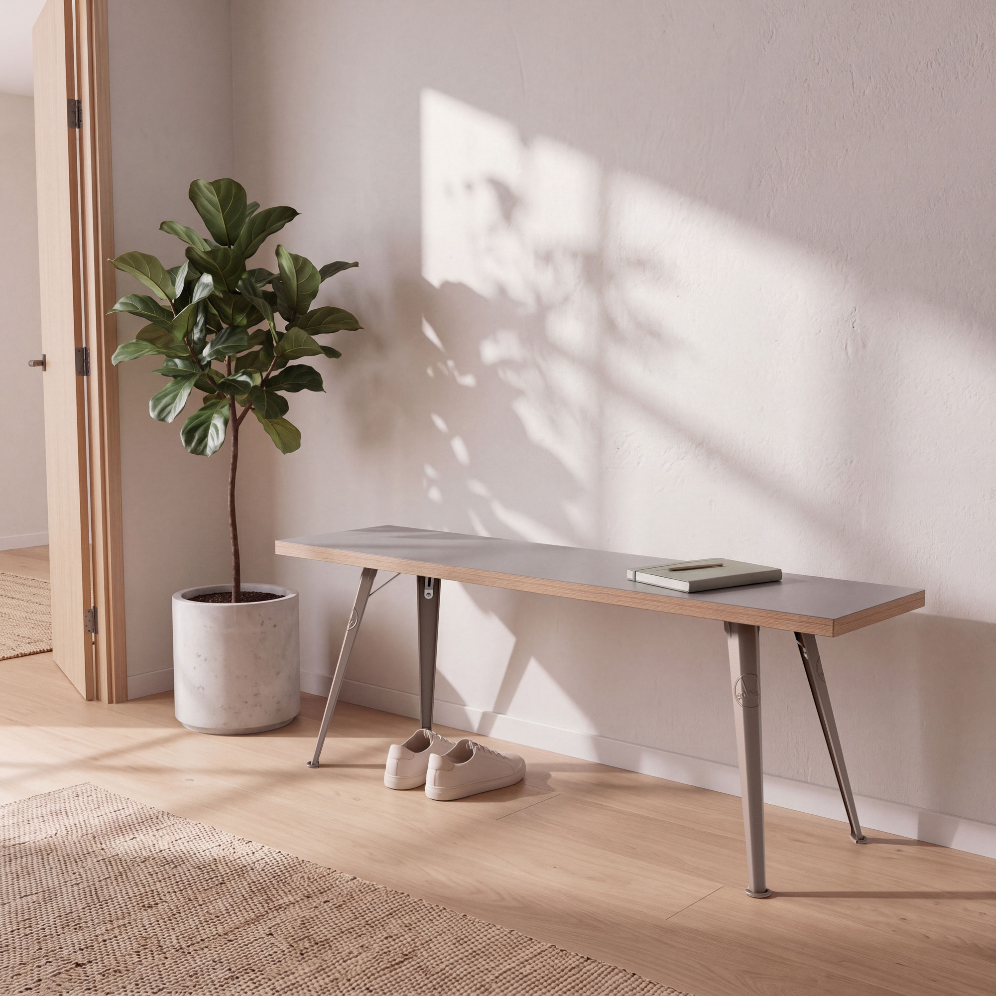 Rowac-Bank in Sonderfarbe Desert Sand aus Metall und Holz, vor weißer Wand mit Pflanze und Sneakers auf Holzfußboden